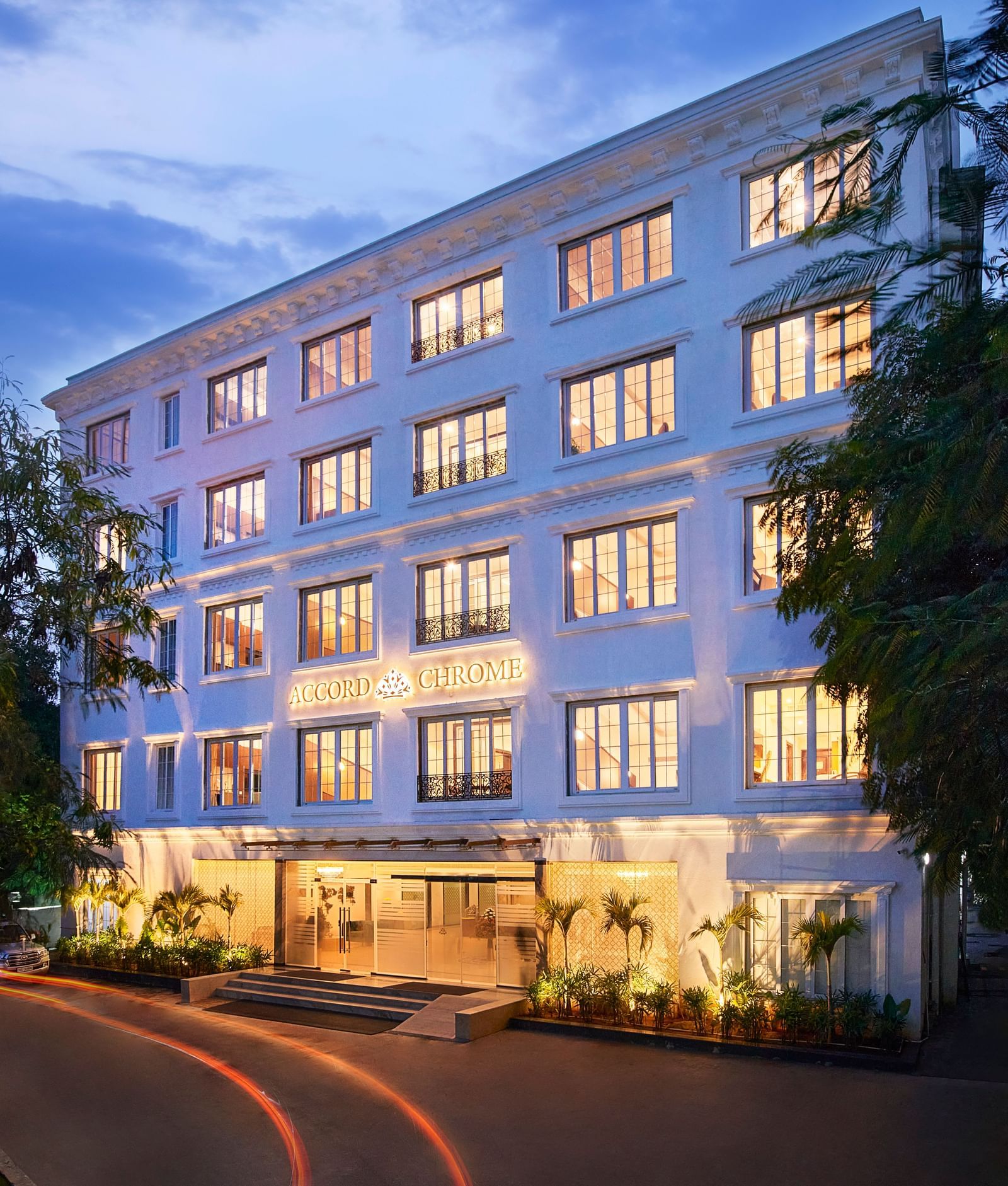 An image of building surrounded by trees on the road